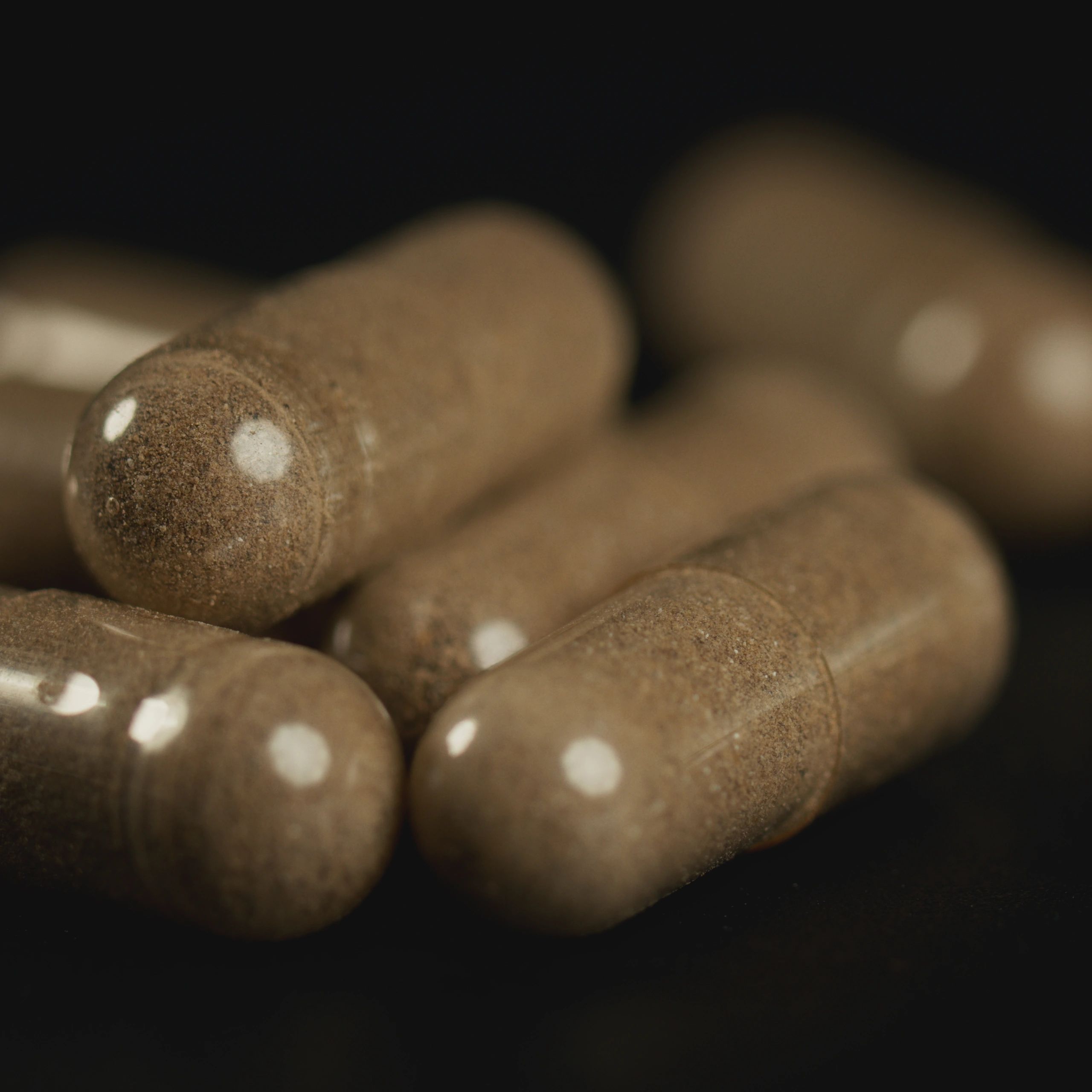 Transparent supplement capsules on a dark textured background